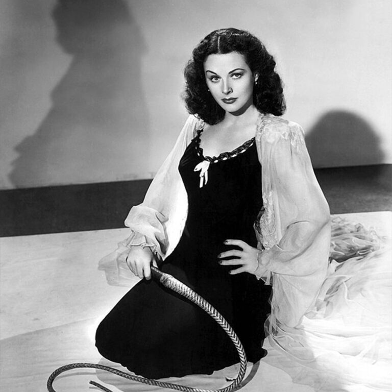 Hedy Lamarr sitting with a whip
